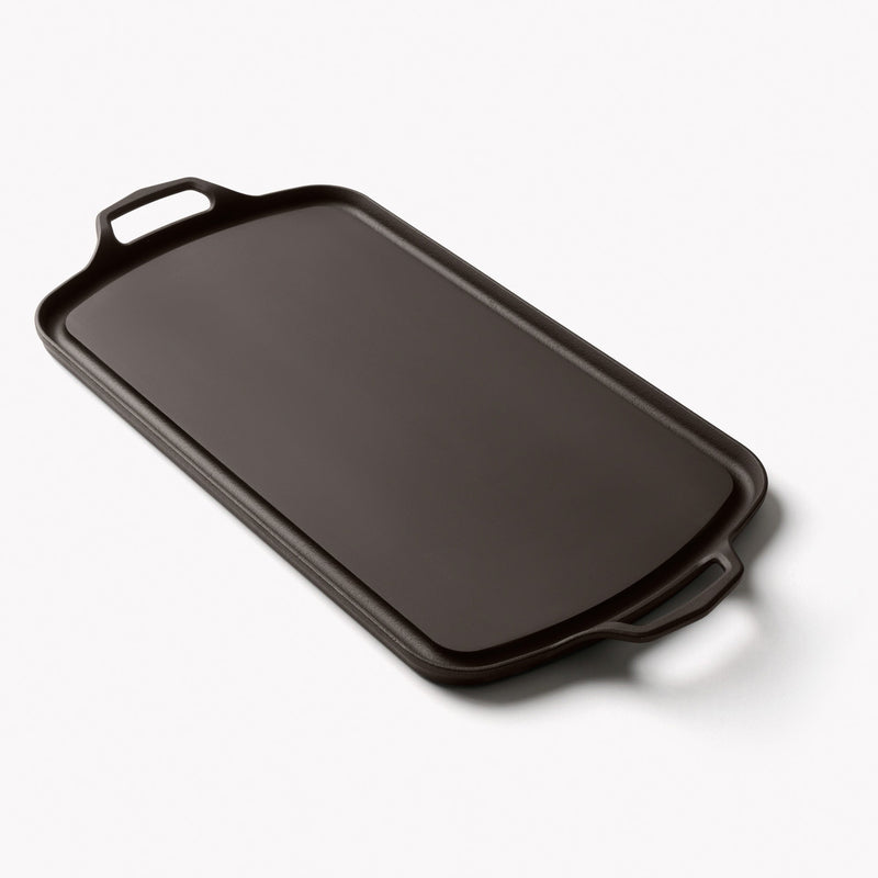 Angled view of the Field Company Long Griddle with a cast loop handle at each end