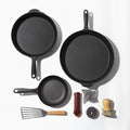 Bird's eye view of all 3 cast iron skillets, cast iron care kit, slotted turner, and mesh scrubber included in kit. thumbnail